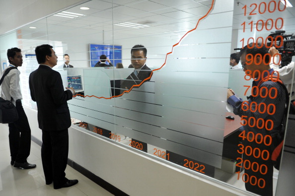 People stand near a stocks graph during launching ceremony at the Cambodian Securities Exchange (CSX)