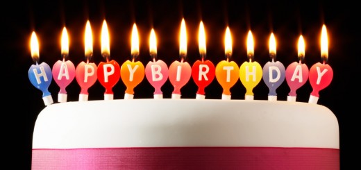 Iced cake lit with happy birthday candles